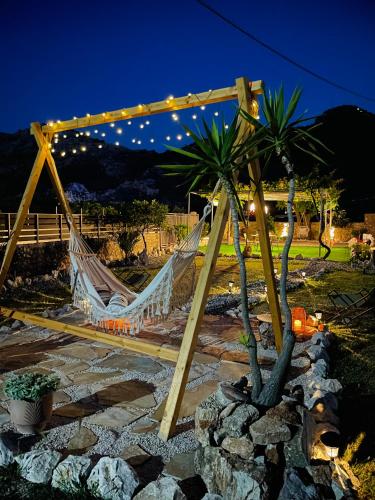 a hammock in a garden with palm trees and lights at Althea Apartments in Kolimbia