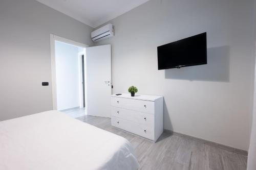 a white bedroom with a bed and a tv on a wall at B&B del Sole in Ercolano
