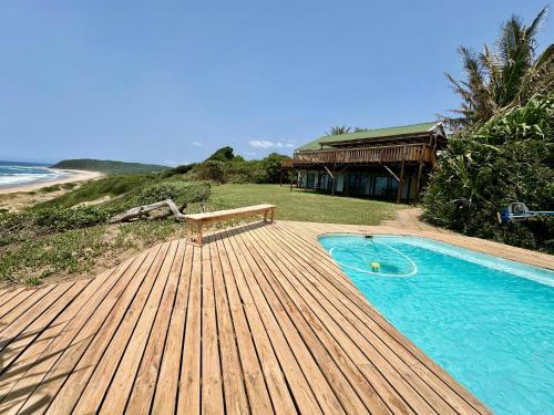 a wooden deck with a swimming pool next to a house at Kangela 1 in Ponta Malongane