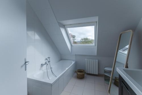 a white bathroom with a tub and a window at AN 19 - Charmante maison a 300m de la mer in Porspoder