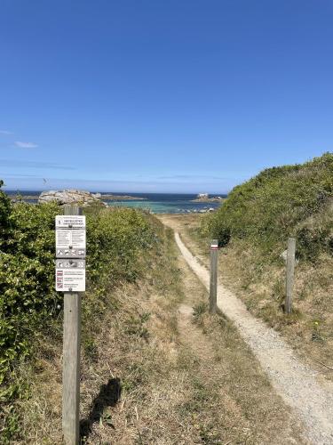 a sign on a dirt road near the ocean at AN 21 - Charmante maison a 300m de la mer in Porspoder