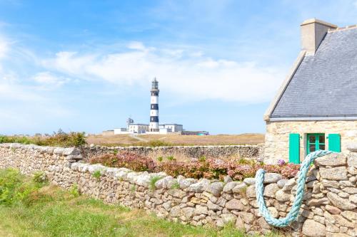 a stone wall with a lighthouse in the background at AN 21 - Charmante maison a 300m de la mer in Porspoder