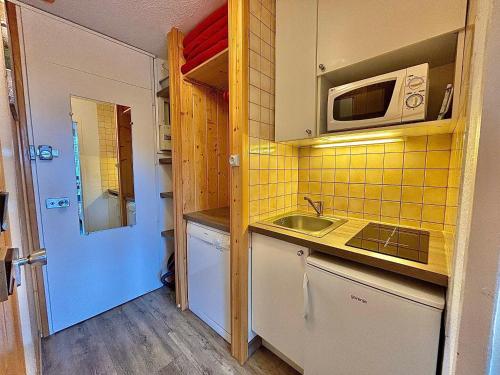 une petite cuisine avec un évier et un micro-ondes dans l'établissement Charmant Studio au Cœur des Menuires, Proche Pistes et Commerces - FR-1-452-127, aux Menuires