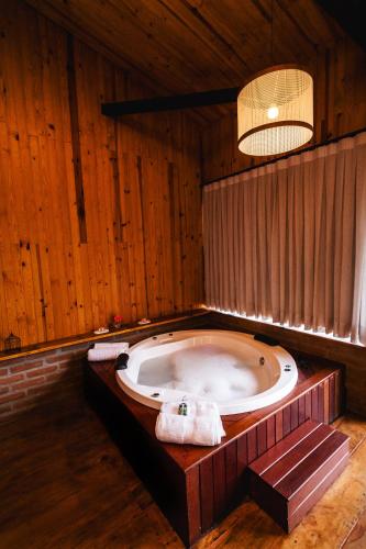 a large bath tub in a room with wooden walls at Estalagem Tronador in Camanducaia