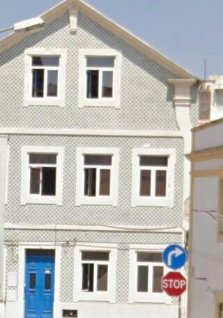 a large white house with blue doors and a stop sign at Private Room 102 in Guest house da Fonte in Figueira da Foz