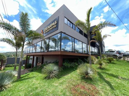 a building with palm trees in front of it at Escarpas Styles Hotel in Capitólio