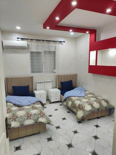 a bedroom with two beds and a red cross on the wall at Jijel in Jijel