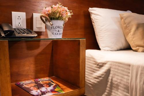 a table with a flower pot on it next to a bed at Hotel del Carmen, en el Centro- DESAYUNO Incluido ! in Tuxtla Gutiérrez