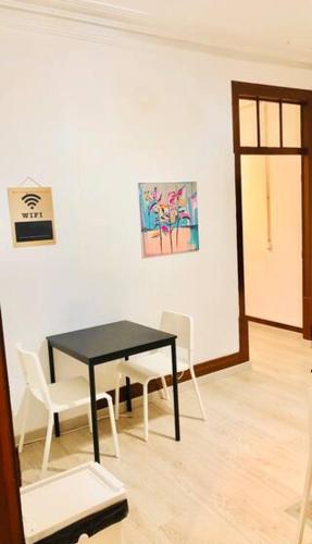 a dining room with a black table and white chairs at Private Room 201 in Guest House da Fonte in Figueira da Foz