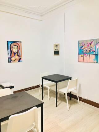 a room with two tables and chairs and paintings on the wall at Private Room 203 in Guest House da Fonte in Figueira da Foz