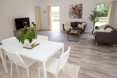 a living room with a white table and chairs at 2 Bedrooms with Garage right on Te Awa River Ride in Tamahere