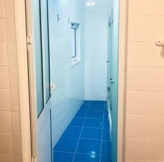 a bathroom with a shower with a blue tile floor at Private Room 204 in Guest House da Fonte in Figueira da Foz