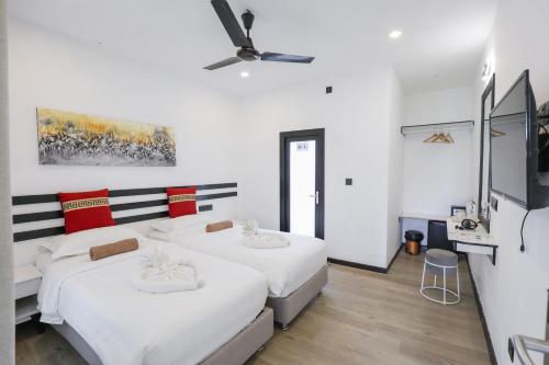 two beds in a white room with a ceiling fan at Belvedere Thoddoo in Thoddoo