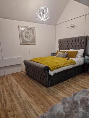 a bedroom with a large bed with a yellow blanket at Ty Branwen in Cowbridge