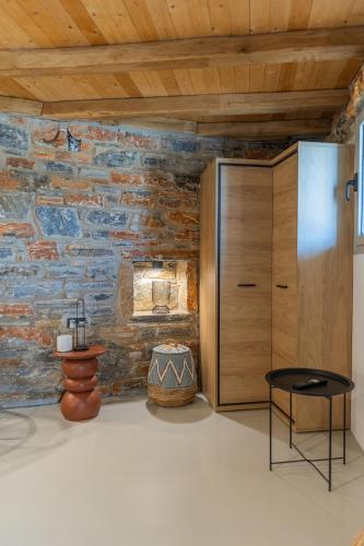 a room with a stone wall and a table and a cabinet at Harmony Luxury Villas Naxos in Kastraki Naxou