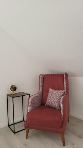 a red chair with a pillow and a side table at Reload Apartments - großzügige Ferienwohnung im Remmeker Feld in Bad Arolsen