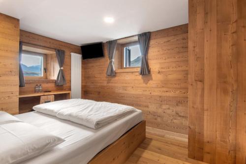 a bedroom with a bed with wooden walls and windows at Agriturismo Montespluga in Madesimo