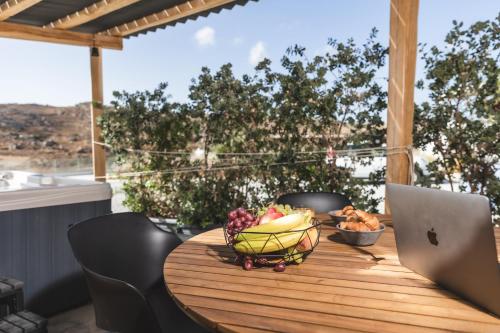 a wooden table with a bowl of fruit and a laptop at Harmony Luxury Villas Naxos in Kastraki Naxou