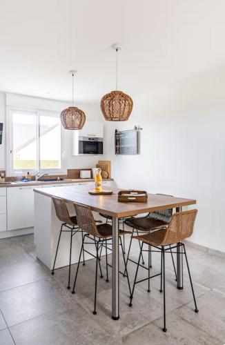 une cuisine avec une table et des chaises en bois dans l'établissement Maison plain-pied 4 chambres Graye sur mer plage à 700 m, à Graye-sur-Mer