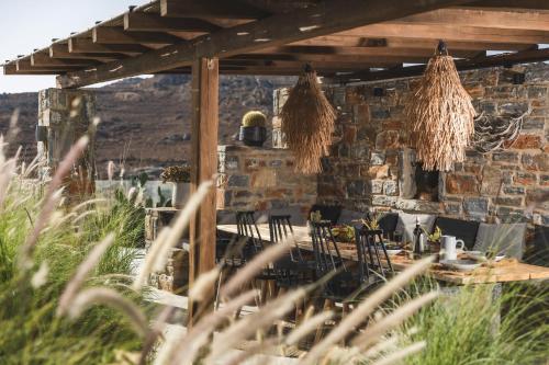 a patio with a table and chairs and a stone wall at Harmony Luxury Villas Naxos in Kastraki Naxou