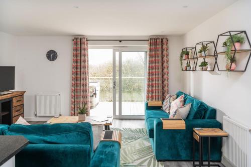 a living room with two blue couches at Waveside-Waterside with hot tubResort PoolGym in Padstow