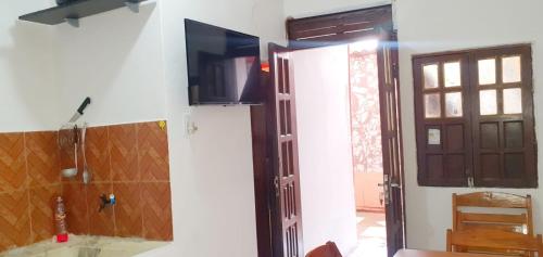 a bathroom with a door and a television on a wall at Three A Diárias in Mata de Sao Joao