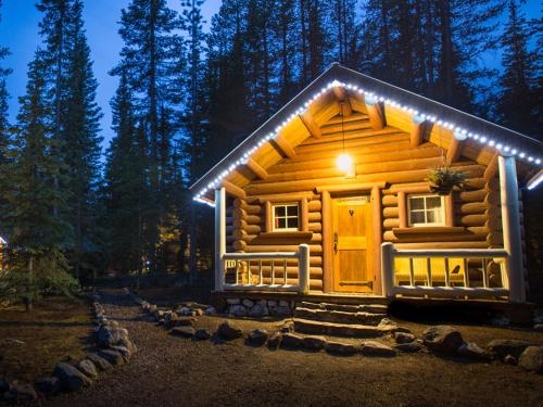 a log cabin with lights on the front of it at Storm Mountain Lodge & Cabins in Banff