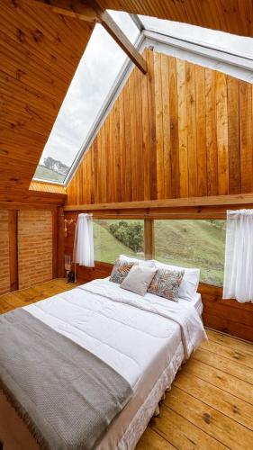 a large bed in a room with a large window at Vilare's da Mantiqueira in Queimada