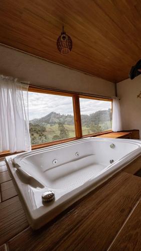 a bath tub in a room with a window at Vilare's da Mantiqueira in Queimada