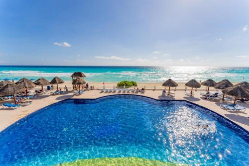 a swimming pool at the beach with umbrellas and chairs at Beachfront Villa in Cancun Hotel Zone in Cancún