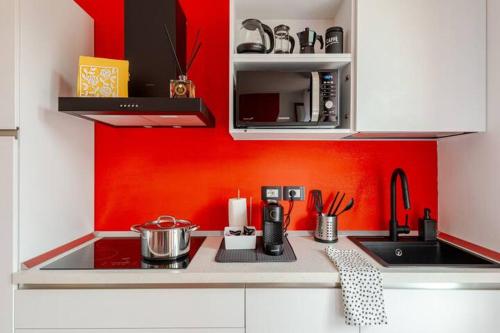a kitchen with a sink and a red wall at Boutique Apartment Family in Chiusi
