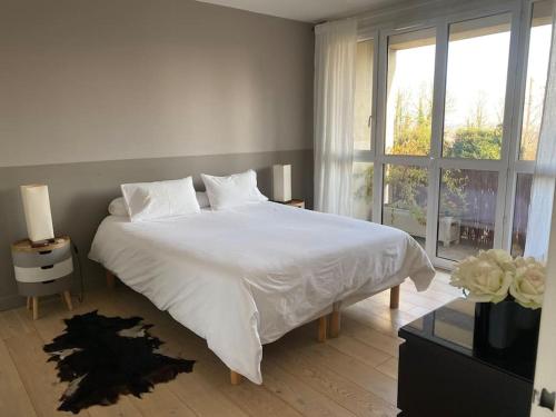 une chambre avec un lit blanc et une fenêtre dans l'établissement Au Milieu des Arbres, à Suresnes