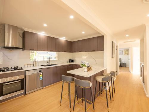 a kitchen with wooden cabinets and a island with bar stools at Super Value 4BR House near Westfield Shops and Parks in Brisbane