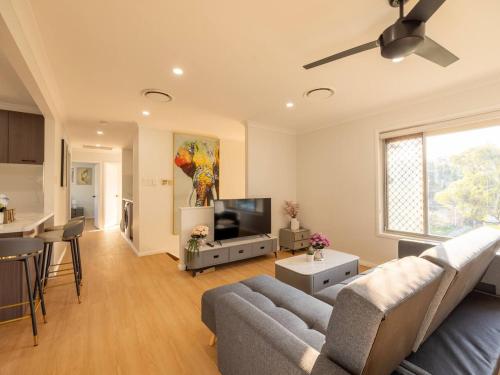 a living room with a couch and a flat screen tv at Super Value 4BR House near Westfield Shops and Parks in Brisbane