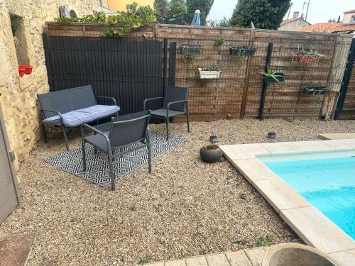 un patio avec deux chaises et une table à côté d'une piscine dans l'établissement Le mazet, à Pélissanne