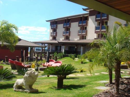 a resort with a garden with palm trees and a building at Flat Life Resort com vista do Lago in Brasilia