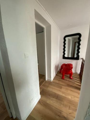 a red teddy bear sitting in a hallway with a mirror at Apparement plein centre ville in Béthune
