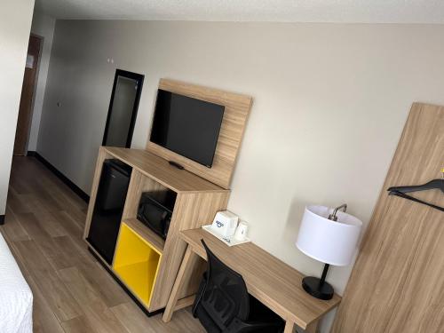 a room with a television and a desk with a lamp at Days Inn by Wyndham Muncie -Ball State University in Muncie