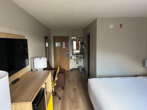 a hotel room with a bed and a desk with a television at Days Inn by Wyndham Muncie -Ball State University in Muncie
