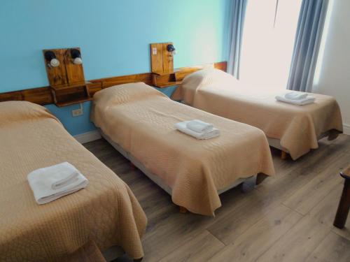 Una habitación con tres camas con toallas. en Casa de Grillos, en El Calafate