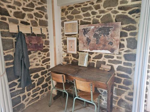 a room with a stone wall with a wooden desk at Ker Adèle, longère cosy au cœur d'un bois in Ploërdut