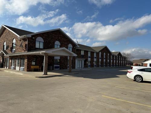 a large brick building with a car parked in a parking lot at Days Inn by Wyndham Muncie -Ball State University in Muncie