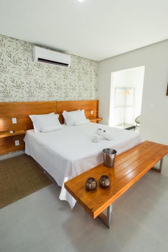 a bedroom with a large white bed and a wooden table at Entre Serras & Águas in Capitólio