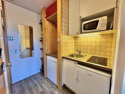 une petite cuisine avec un évier et un micro-ondes dans l'établissement Résidence Chaviere - Studio équipé ski aux pieds idéal couple MAE-4074, aux Menuires
