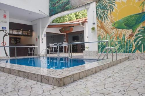 a building with a swimming pool in front of a mural at Riosol Hotel Tarapoto in Tarapoto