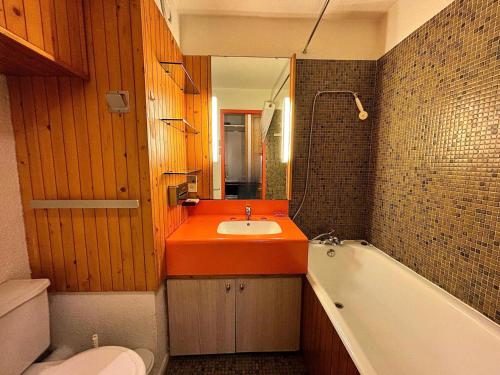 La salle de bains est pourvue d'un lavabo orange et d'une baignoire. dans l'établissement Résidence Chaviere - Studio ski aux pieds au coeur des Ménuires MAE-6174, aux Menuires