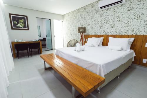 a bedroom with a large bed and a wooden bench at Entre Serras & Águas in Capitólio