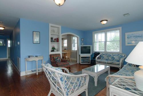 a living room with blue walls and a couch and chairs at Craft Upper Unit by Bryant Real Estate in Wrightsville Beach