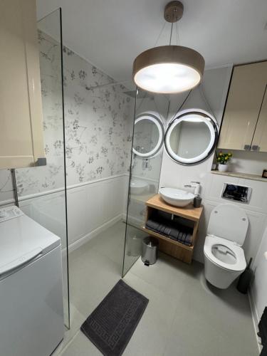 a bathroom with a toilet and a sink and mirrors at Central Apartment in Târgu Jiu