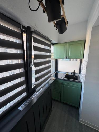 a kitchen with green cabinets and a sink and a window at Central Apartment in Târgu Jiu